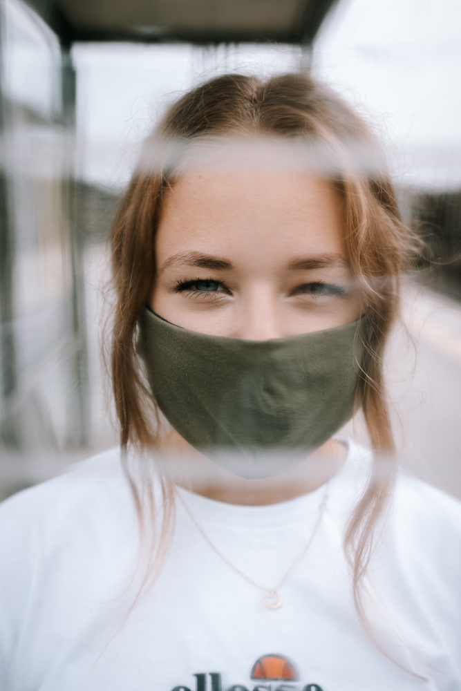 Urban Portrait Shooting - Frau mit Maske hinter einer Glasscheibe