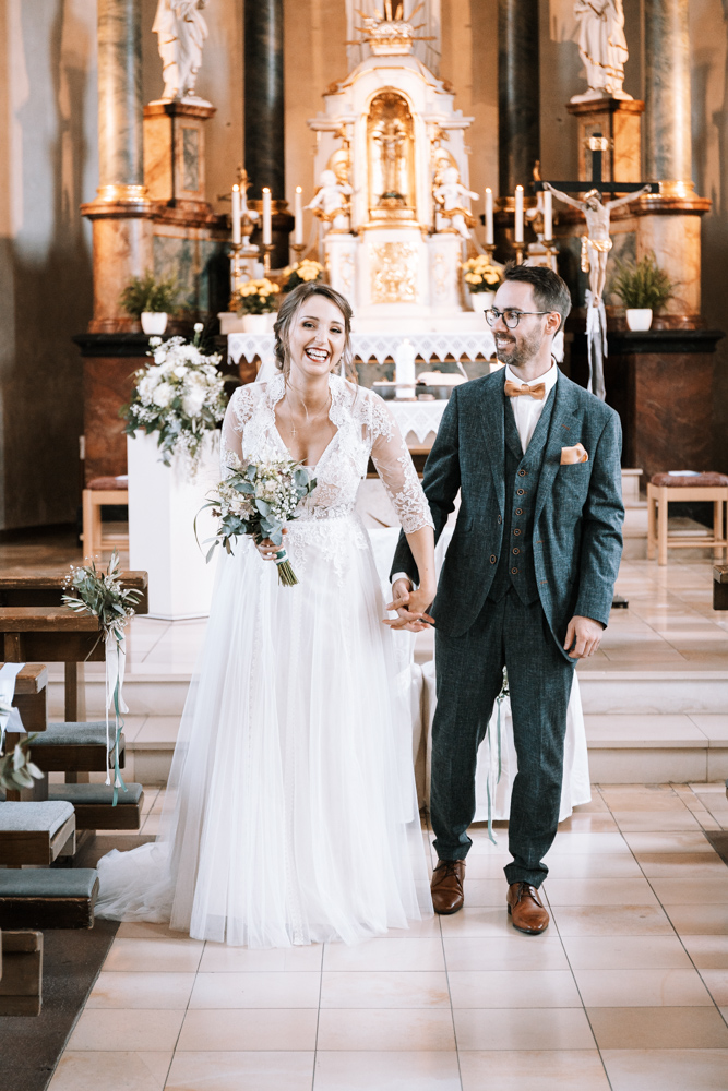 Hochzeitsshooting - Kirche - Braut und Bräutigam, Hand in Hand, gehen lachend